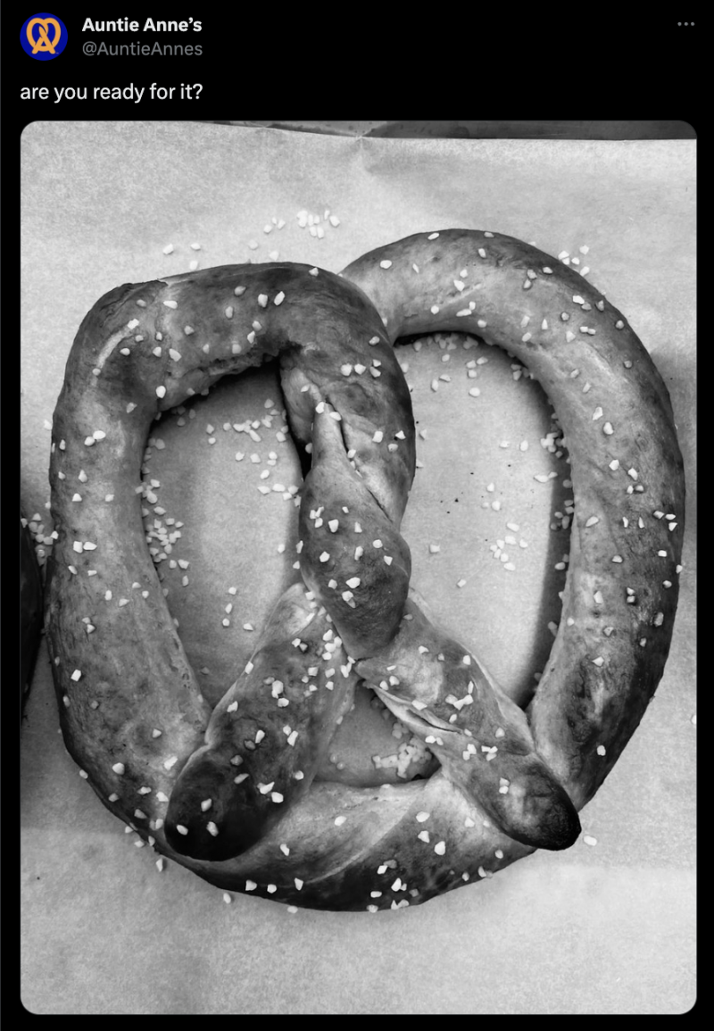   Une capture d'écran d'une publication sur X (anciennement Twitter) de tante Anne's. The caption reads, "are you ready for it?" and is accompanied by a black and white photo of a delicious-looking soft pretzel.